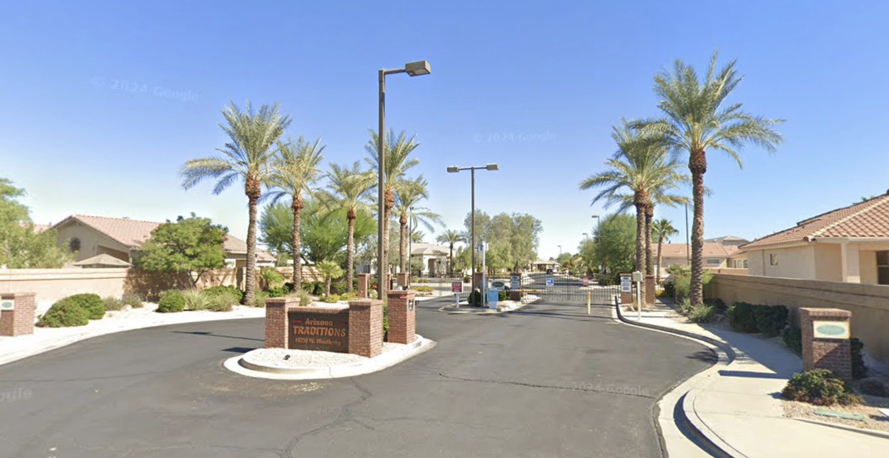 Arizona Traditions gated entrance with palm trees and community monument sign
